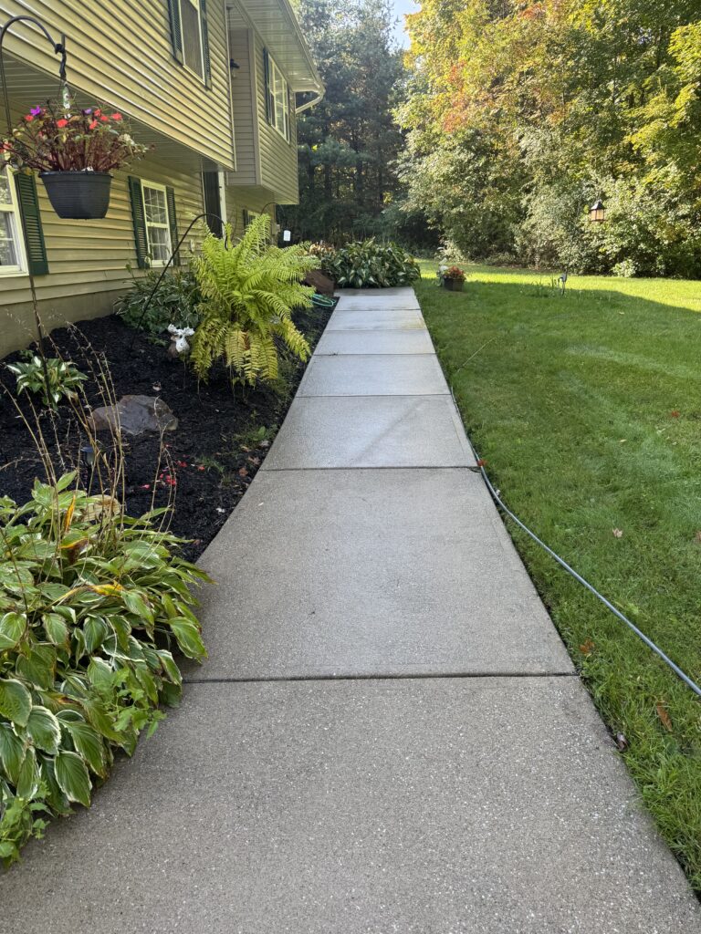 Refreshed sidewalk after concrete cleaning by Wiley's Pressure Washing Service in Thompson OH.