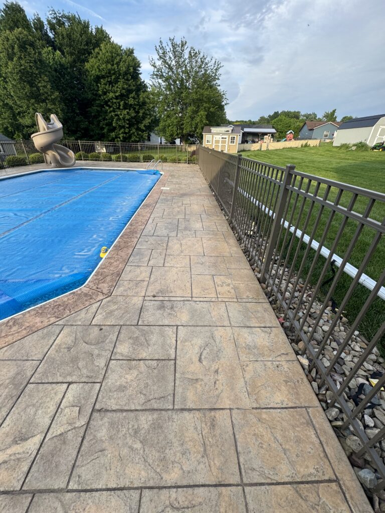 Backyard with a fenced-in in-ground pool covered by a blue safety cover, paved patio, and a slide on the left.
