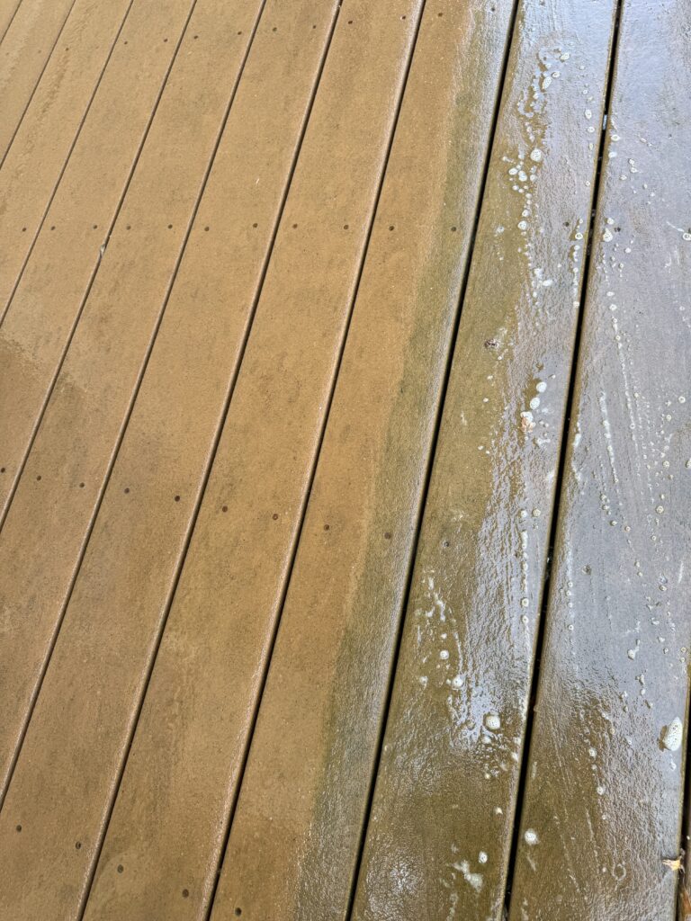 Wooden deck planks, mostly dry brown with a wet, foamy streak along the right edge.