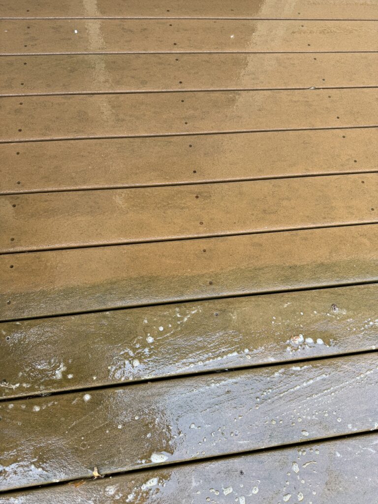 Wet wooden deck or boardwalk with seawater pooling and white foam at the bottom edge.