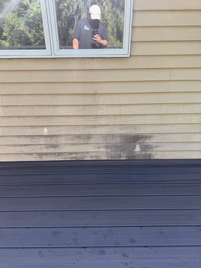Reflection in a square window with greenery outside before being washed by Wiley's pressure Washing Services in Madison, OH