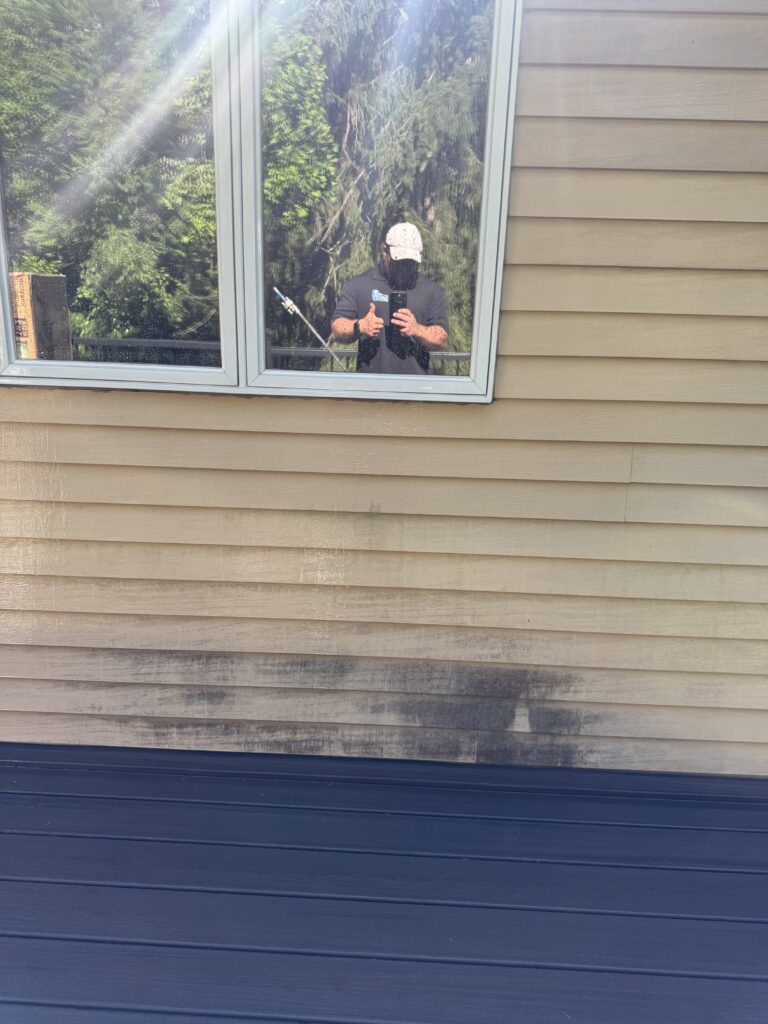 Reflection in a square window with greenery outside before being washed by Wiley's pressure Washing Services in Madison, OH