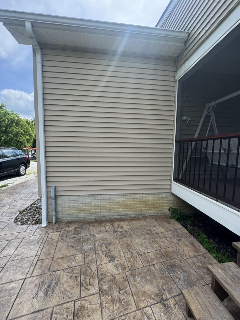 Exterior corner of a house with beige siding, a stamped concrete patio cleaning from Wiley's Pressure Washing Services in Madison, OH