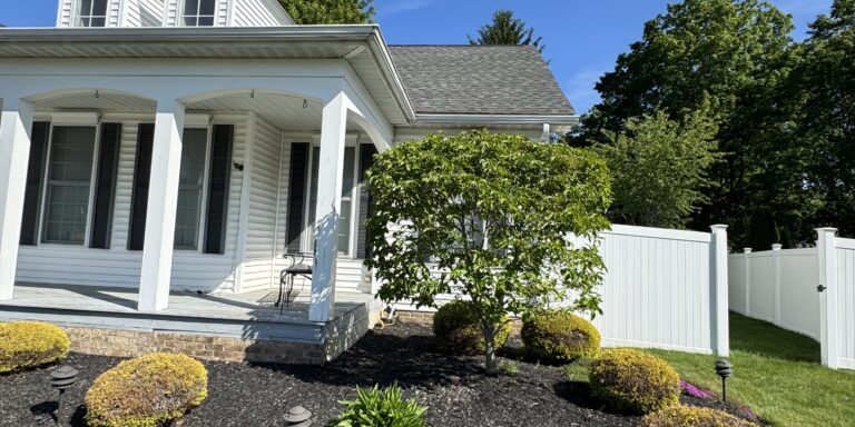 White siding house with a covered front porch, dormer windows, and a manicured black-mulch garden that was cleaned by wiley's pressure washing services in perry, oh